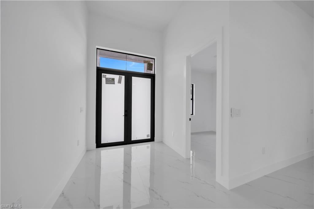 Entrance foyer with light marble finish floors and french doors