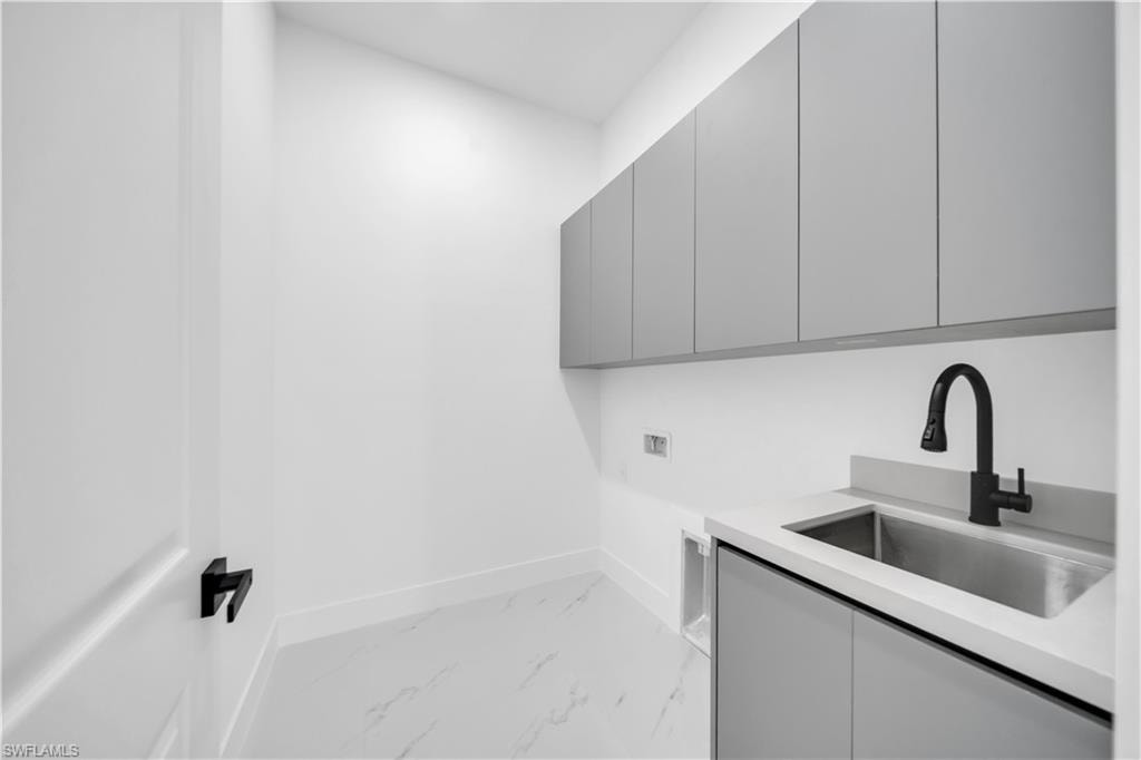 Laundry area with light marble finish flooring, cabinet space, and washer hookup