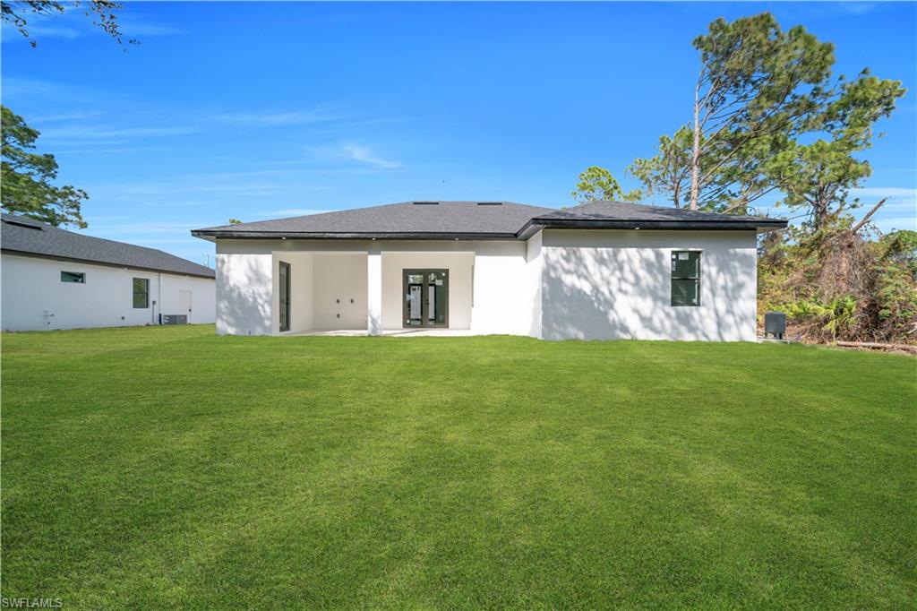 Rear view of house with a yard, a patio area, and stucco siding