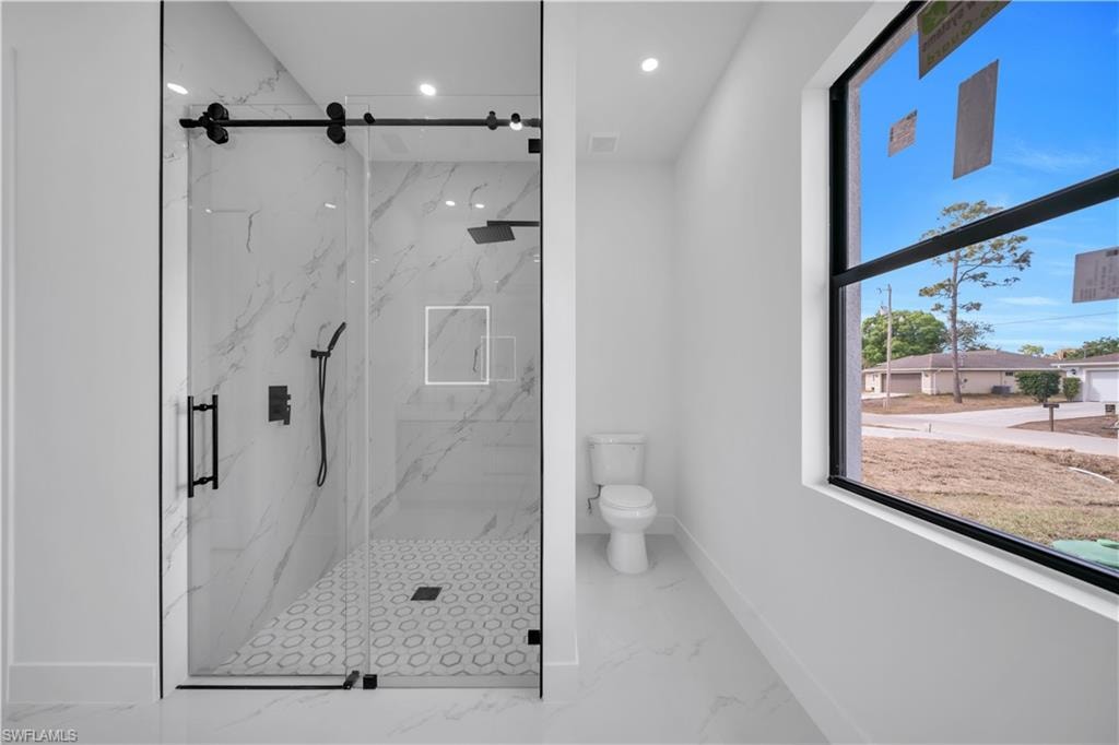 Bathroom with a tile finish shower, marble finish floors, and recessed lighting