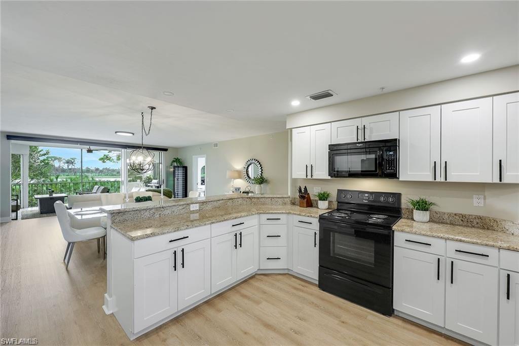 Kitchen featuring black appliances, a peninsula, white cabinetry, light wood-type flooring, and light stone countertops