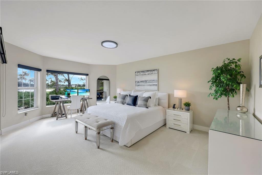 Bedroom featuring light carpet and arched walkways