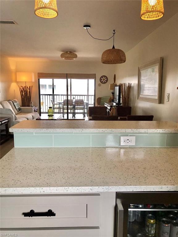 Kitchen featuring white cabinetry, beverage cooler, light stone counters, and open floor plan
