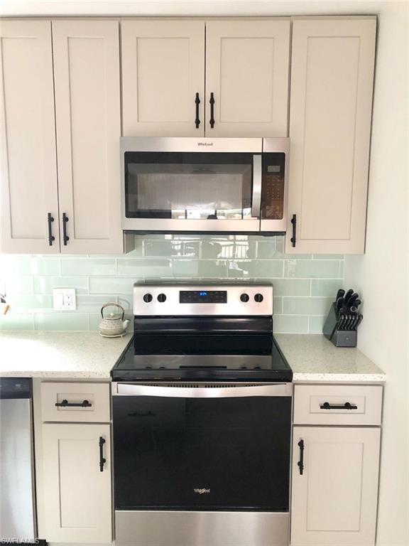 Kitchen with stainless steel appliances, light stone countertops, and tasteful backsplash