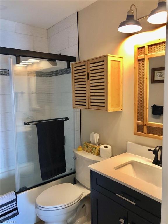 Full bathroom with combined bath / shower with glass door and vanity