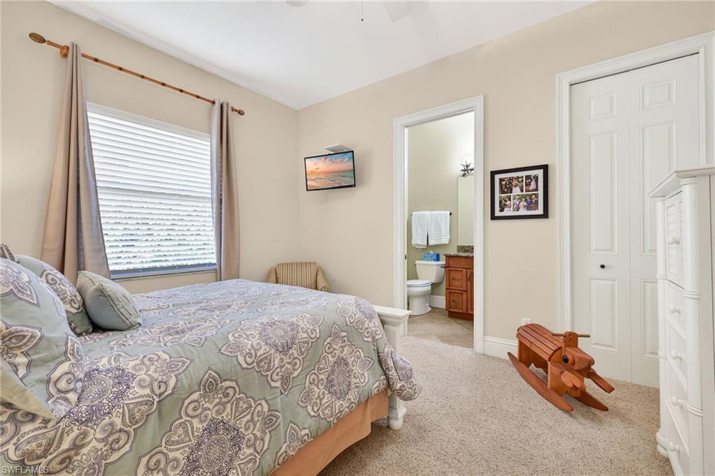 Bedroom with light carpet, ensuite bath, and ceiling fan