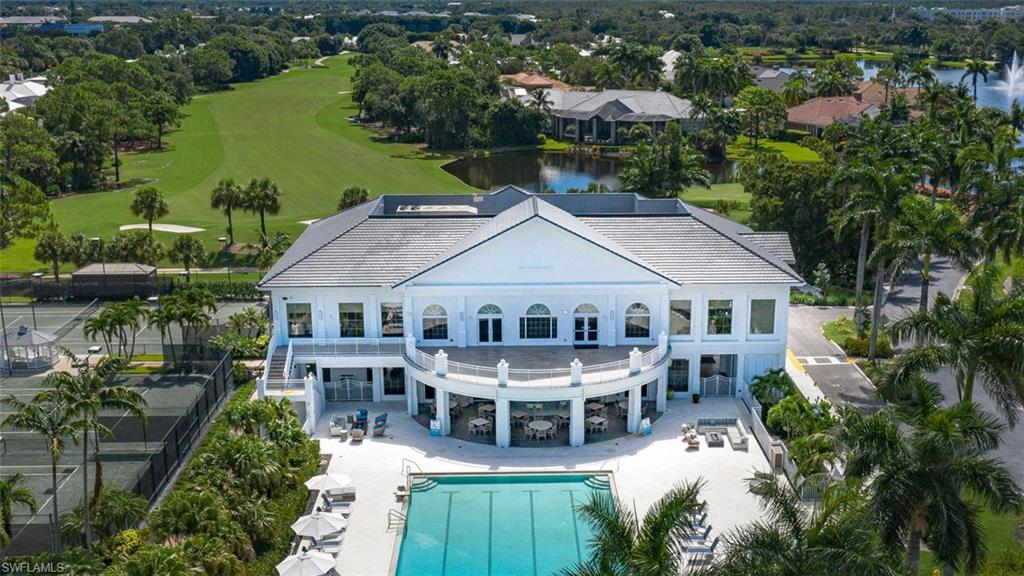 Back of house with a patio, a community pool, a water view, golf course view, and view of wooded area
