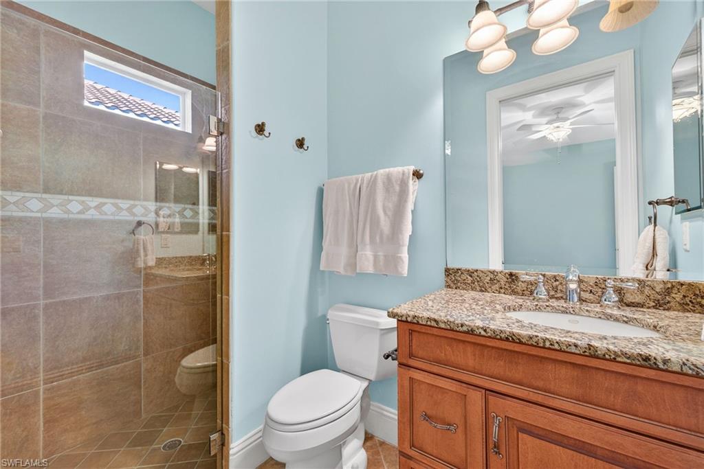 Full bath with a stall shower, vanity, and ceiling fan