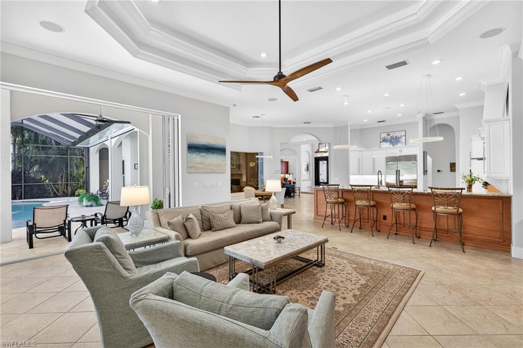 Living room with arched walkways, a ceiling fan, a sunroom, recessed lighting, and crown molding