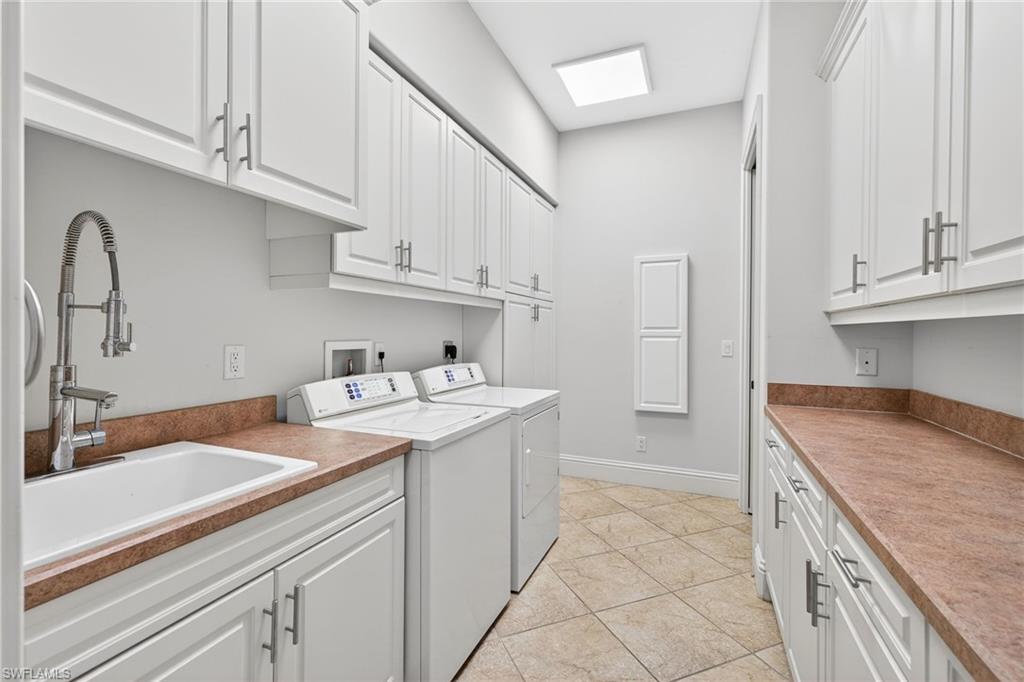 Laundry area with cabinet space, washer and dryer, and light tile patterned flooring