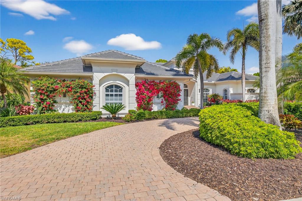 View of front facade featuring a tile roof, stucco siding, and curved driveway