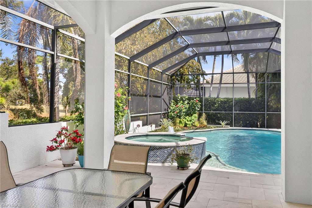 Relaxing pool / spa with outdoor dining area, glass enclosure, a sunroom, and a patio