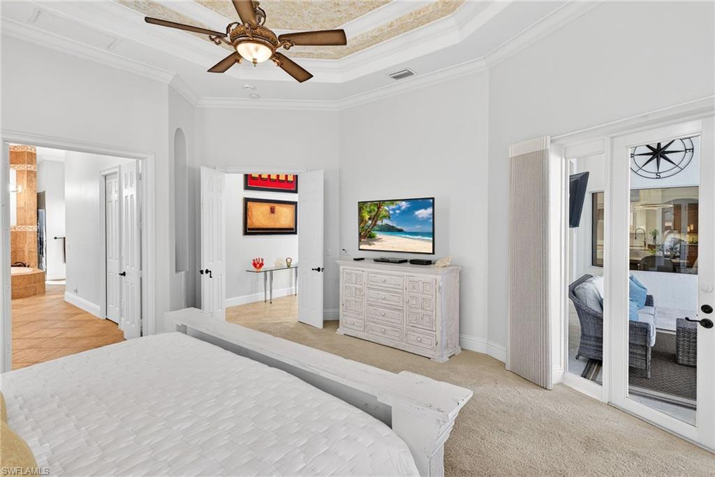 Bedroom with ornamental molding, access to exterior, a raised ceiling, ceiling fan, and light colored carpet