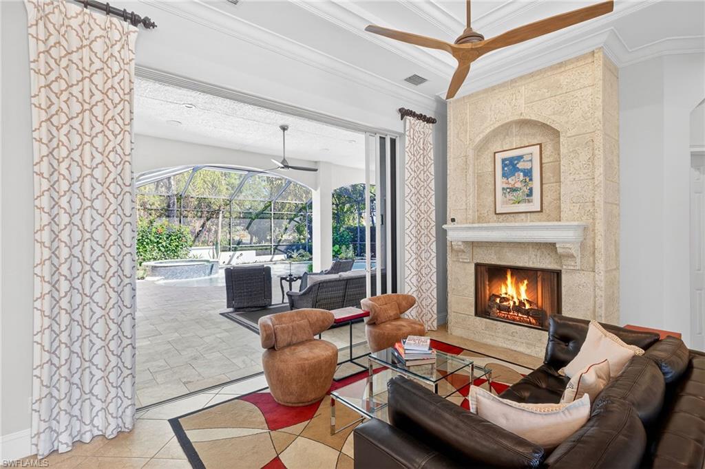 Living room with a sunroom, a ceiling fan, ornamental molding, a tile fireplace, and tile patterned flooring