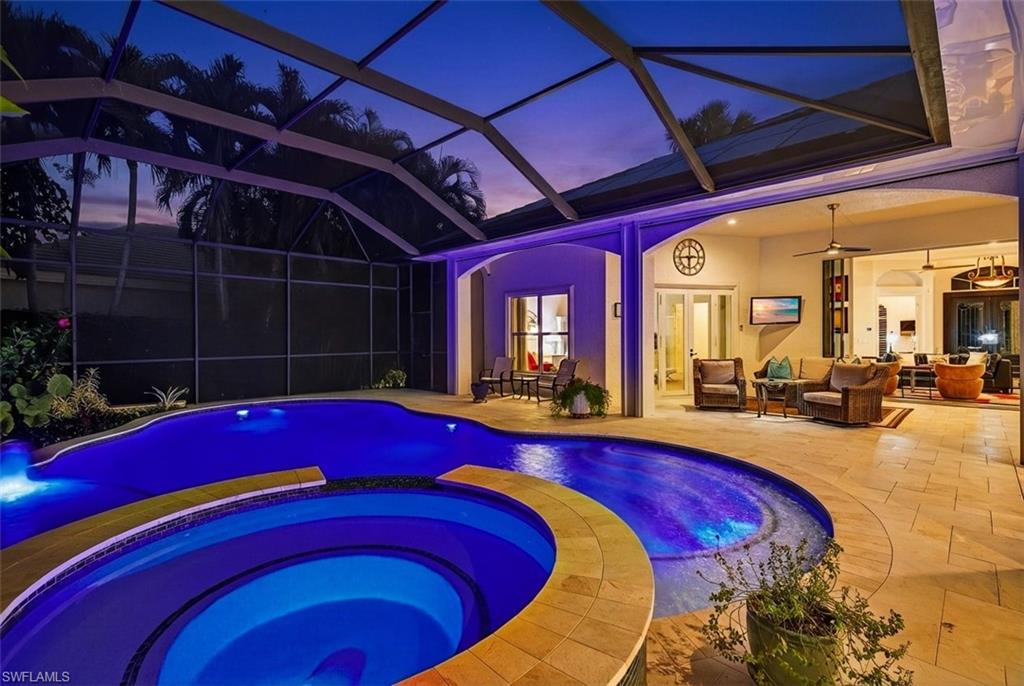 Pool at dusk with a lanai, a pool with connected hot tub, a patio, outdoor furniture, and a sunroom