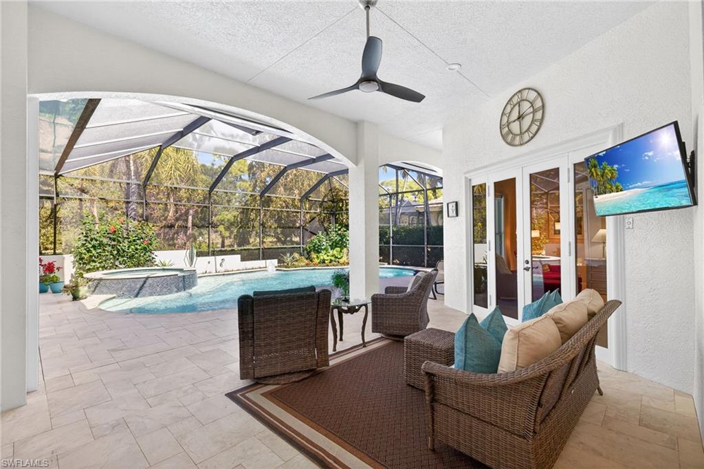 View of patio / terrace with a sunroom, glass enclosure, a pool with connected hot tub, ceiling fan, and french doors