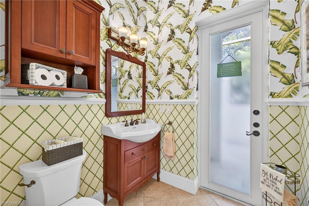 Half bathroom featuring wallpapered walls, vanity, and light tile patterned floors