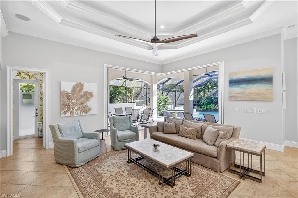 Living area featuring a sunroom, ceiling fan, light tile patterned floors, and ornamental molding