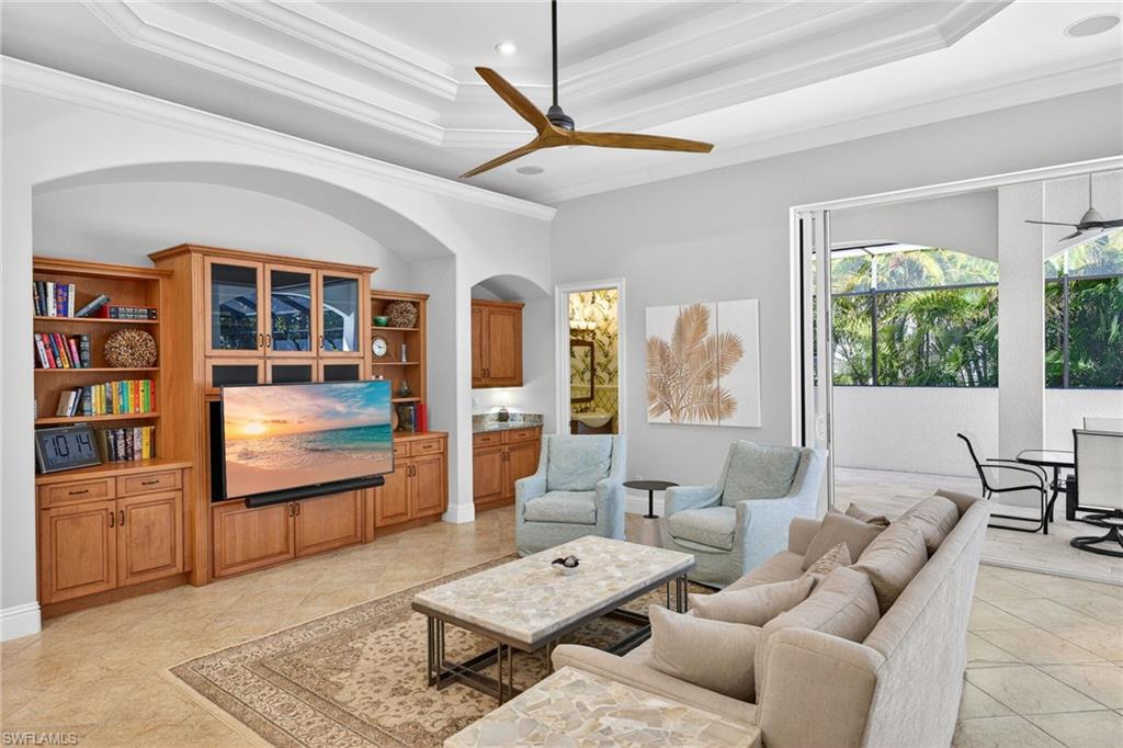 Living area with ceiling fan, crown molding, arched walkways, recessed lighting, and a tray ceiling