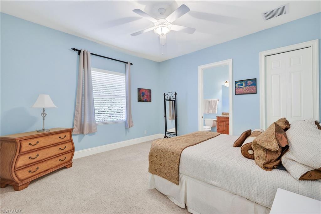 Carpeted bedroom featuring ceiling fan and ensuite bath