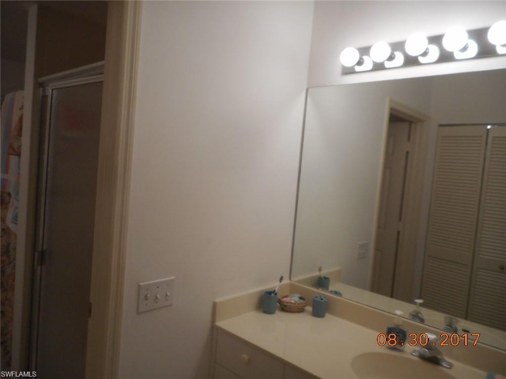 Full bath featuring vanity, a stall shower, and a closet
