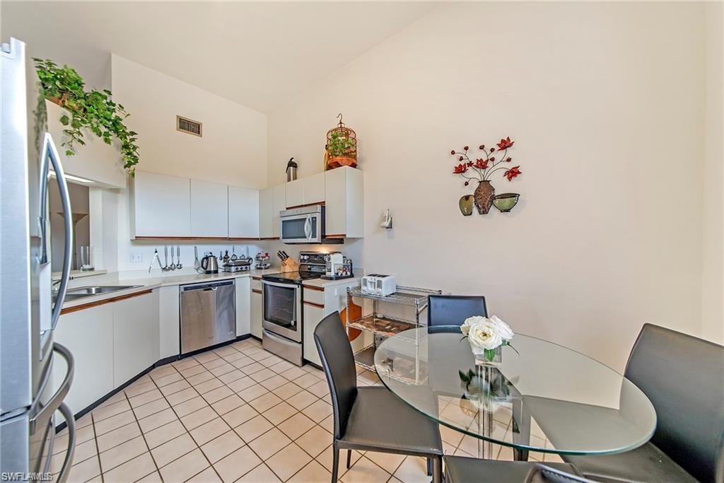 Kitchen with white cabinetry, stainless steel appliances, light countertops, light tile patterned floors, and lofted ceiling