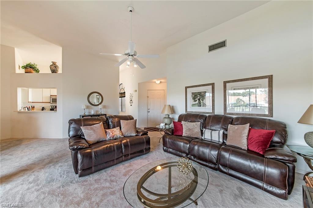 Living area with carpet floors, a ceiling fan, and vaulted ceiling