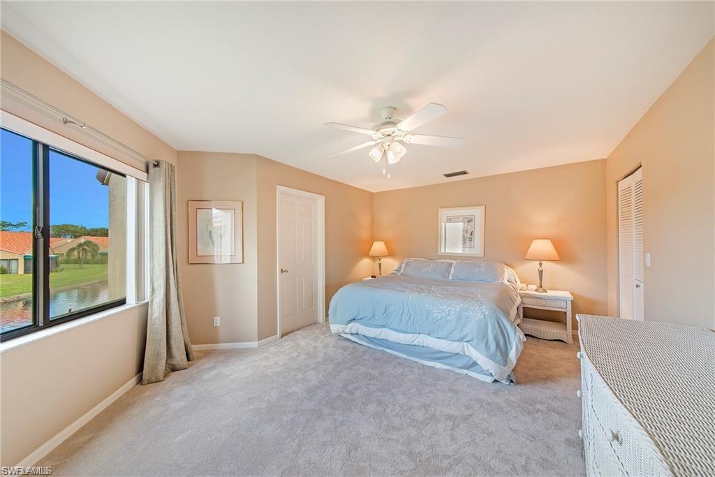 Carpeted bedroom featuring a closet, ceiling fan, and a water view