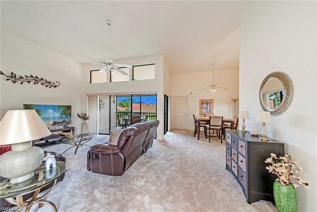 Living room featuring a high ceiling, carpet flooring, and ceiling fan