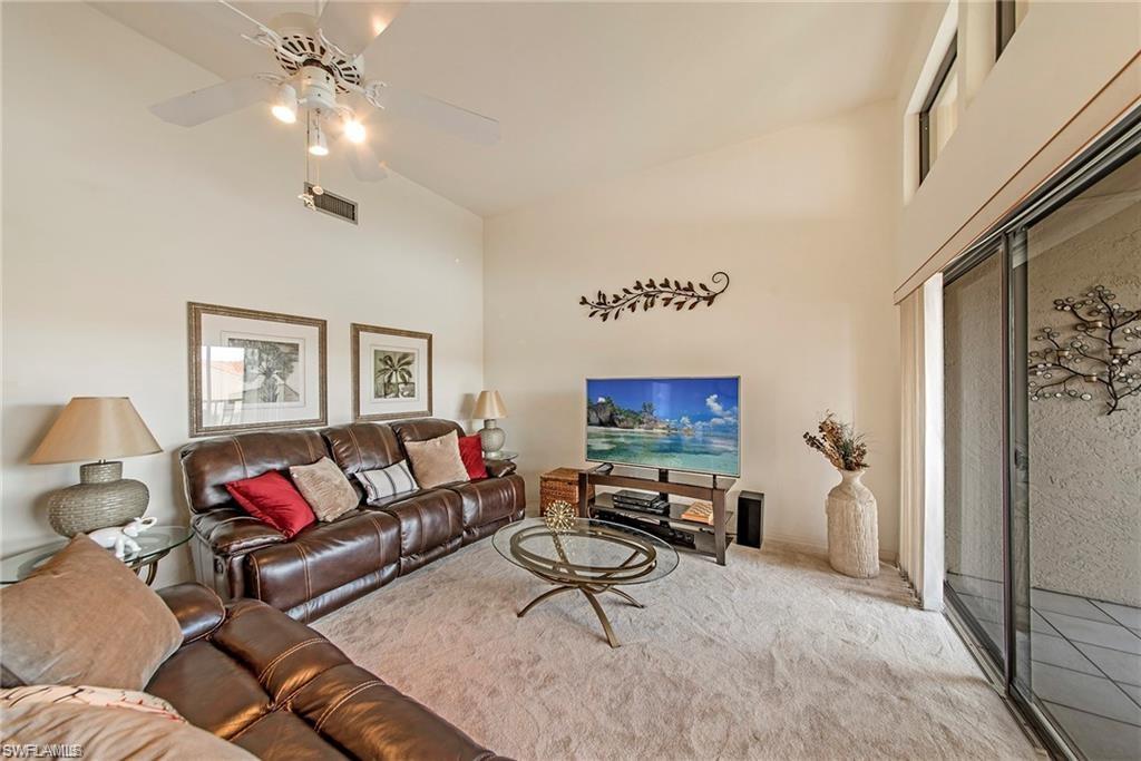 Living area with vaulted ceiling, ceiling fan, and carpet