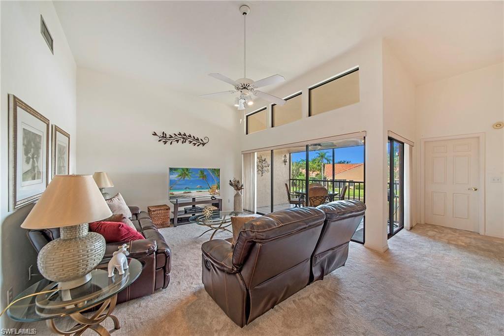 Living room with a high ceiling, carpet floors, and ceiling fan