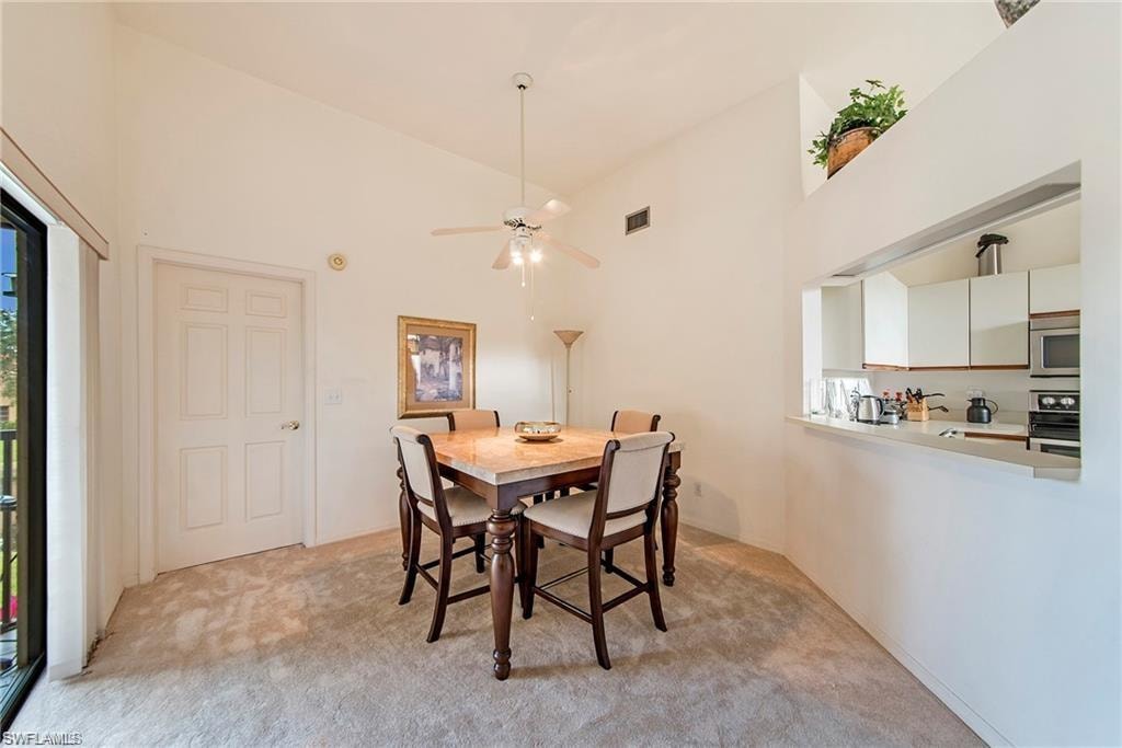 Dining space featuring lofted ceiling, light carpet, and a ceiling fan