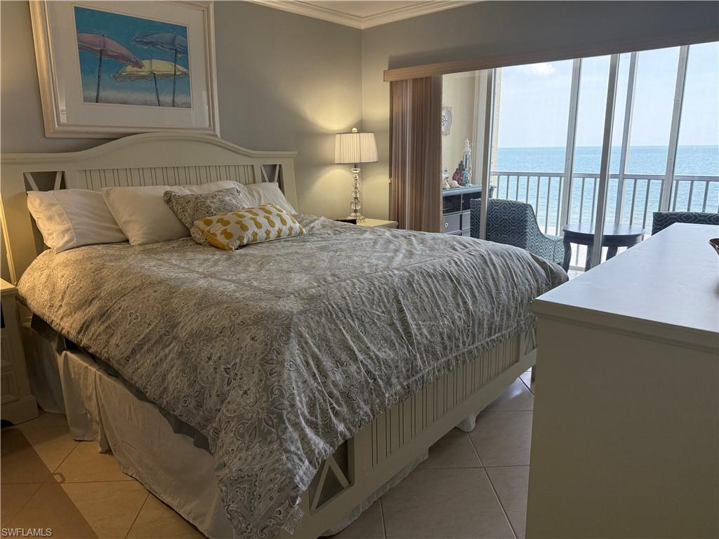 Bedroom featuring a water view, ornamental molding, light tile patterned floors, and access to outside