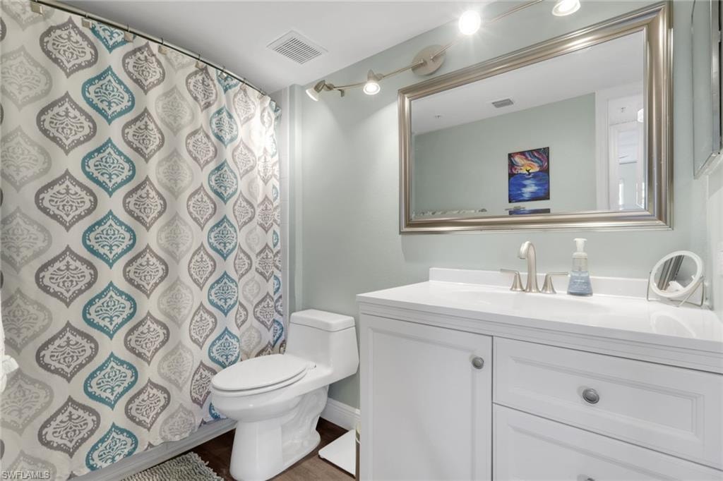 Full bath with vanity, a shower with shower curtain, and dark wood-style floors