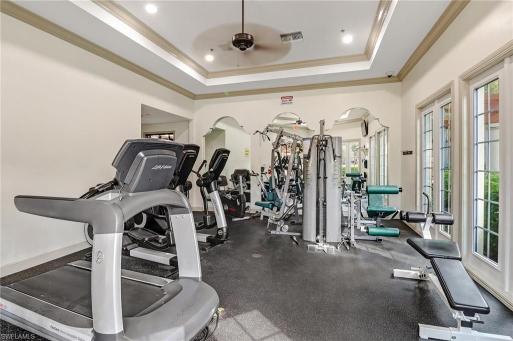 Workout area with ornamental molding, ceiling fan, and a tray ceiling