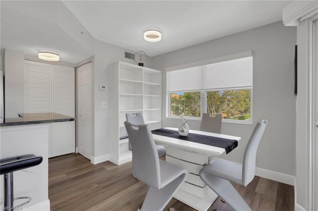 Dining area with a textured ceiling and dark wood-style floors