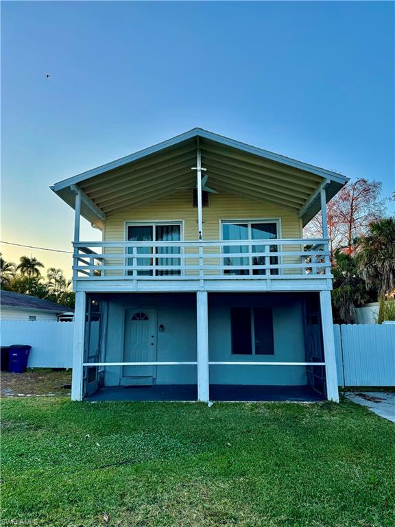 Back of house at dusk featuring a balcony and stucco siding