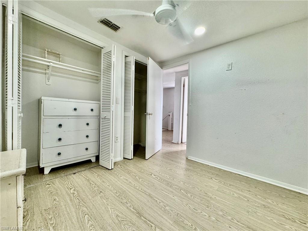 Bedroom featuring light wood-style floors, a closet, a ceiling fan, and a textured wall