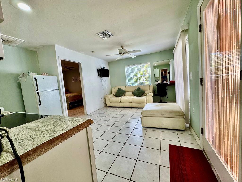 Living room featuring light tile patterned flooring, a ceiling fan, and a textured ceiling