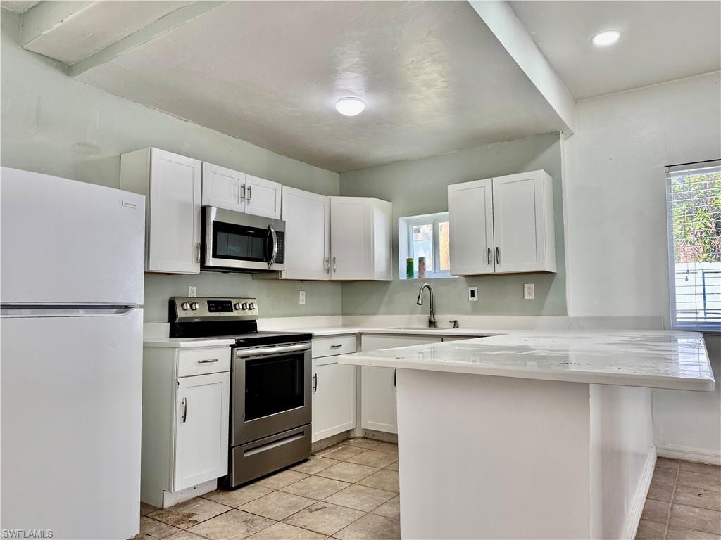 Kitchen featuring stainless steel appliances, a peninsula, white cabinets, and a breakfast bar area