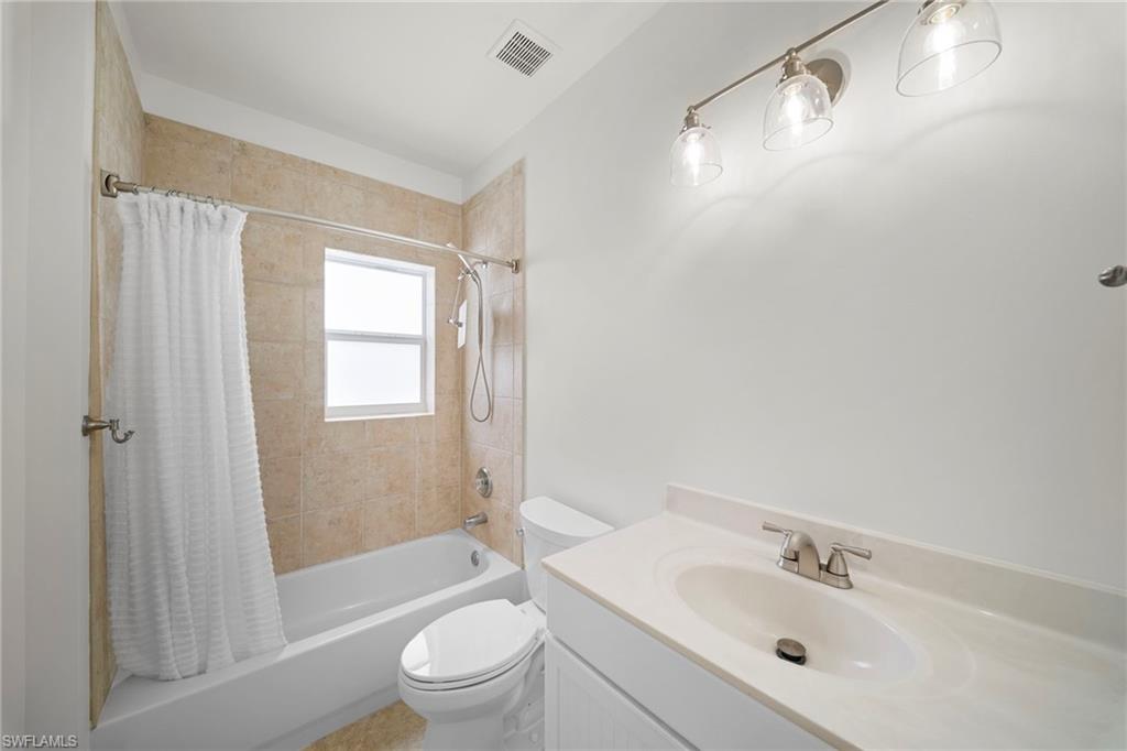 Bathroom featuring a white vanity with an integrated sink, brushed nickel faucet, and a three-light fixture above