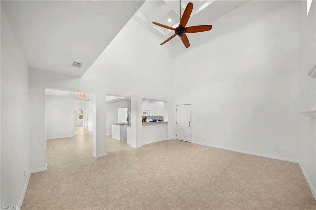 Spacious living area featuring a high vaulted ceiling with a decorative wood-finish ceiling fan and recessed lighting