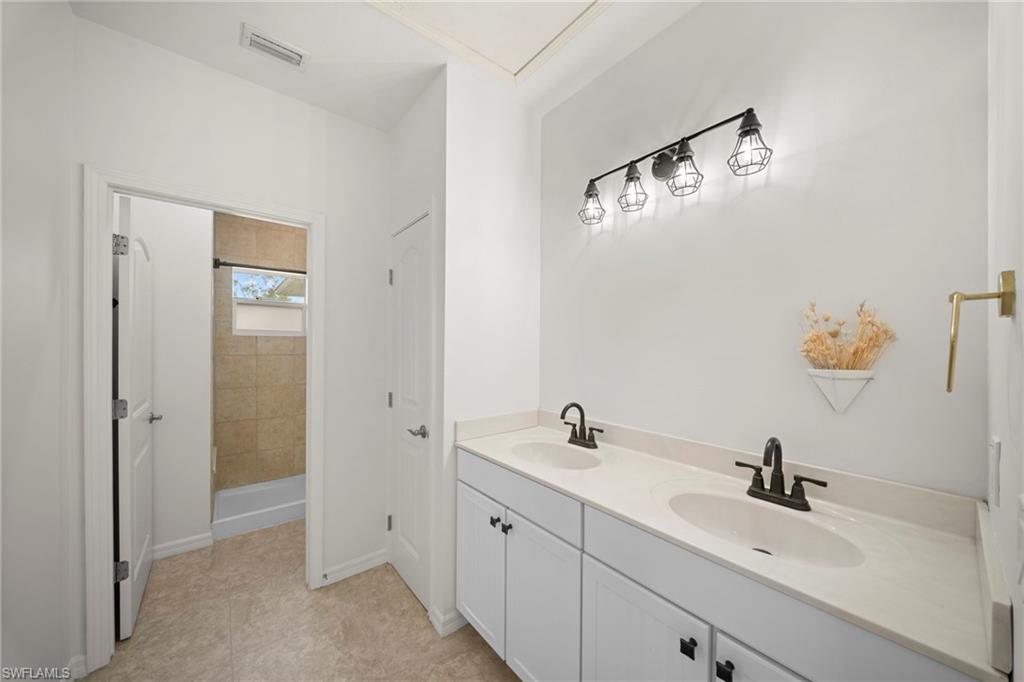 Double vanity with white cabinetry, light-toned countertops, and matte black fixtures