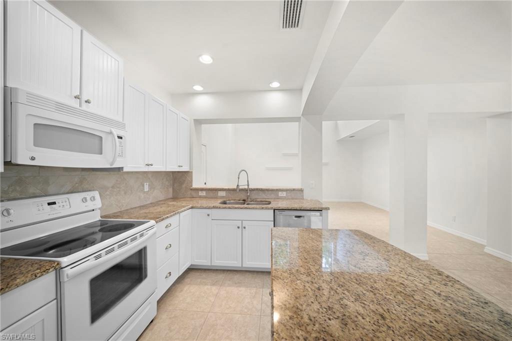Kitchen featuring white cabinetry, light granite countertops, a tile backsplash, and a stainless steel sink with a gooseneck faucet