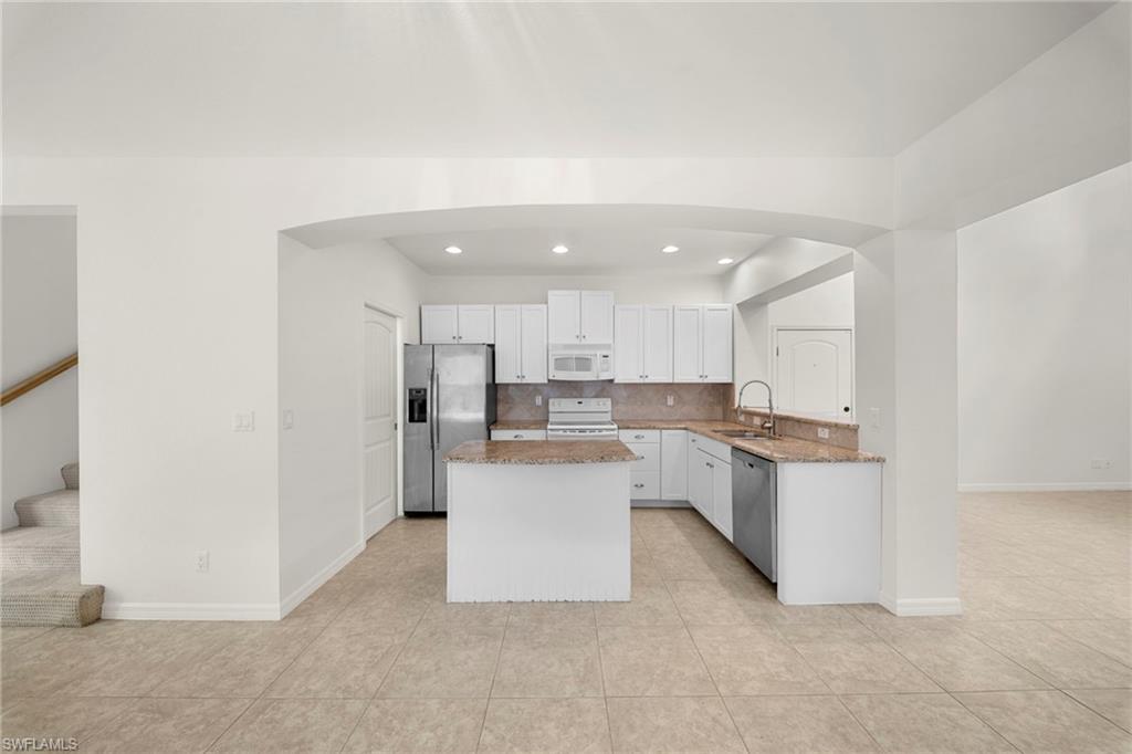 Kitchen featuring a center island, white cabinetry, granite countertops, and stainless steel appliances