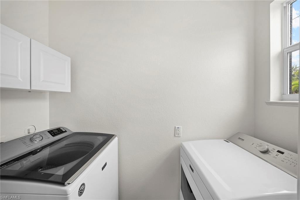 Dedicated utility area featuring overhead white cabinetry and natural light from a window
