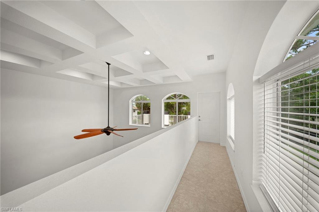 Upper-level hallway featuring a coffered ceiling and a ceiling fan with wood-finish blades