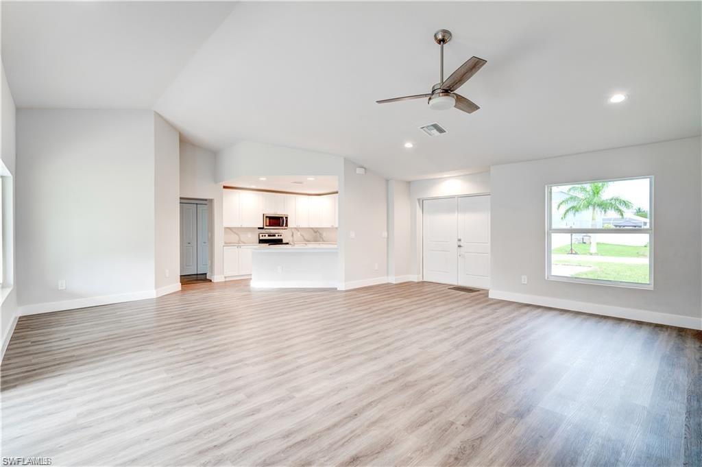 Unfurnished living room featuring a ceiling fan, light wood-style floors, recessed lighting, and vaulted ceiling