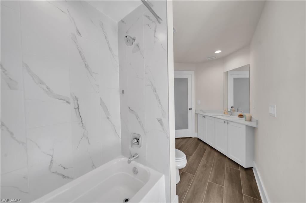 Full bath with shower / washtub combination, vanity, recessed lighting, and wood tiled floors
