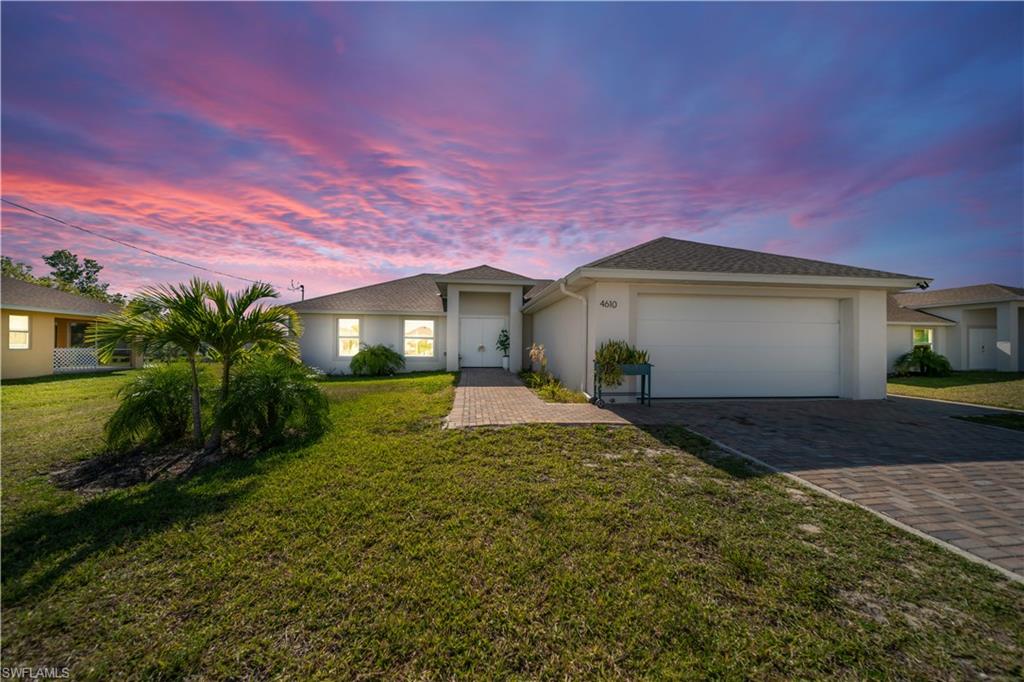 Single story home with a yard, stucco siding, and decorative driveway